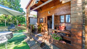 A wooden cabin with a porch, outdoor seating, and a small garden area. - Chalet "Gîte" with Private Pool, Wi-Fi, and Air Conditioning (St Paulet de Caisson)
