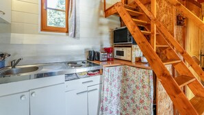 A kitchen with a wooden staircase, a window with a towel, and a microwave on the counter. - Chalet "Gîte" with Private Pool, Wi-Fi, and Air Conditioning (St Paulet de Caisson)
