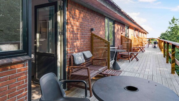 A covered outdoor seating area with brick walls and wooden furniture. - 5 Star Holiday Home in Svaneke (Svaneke)
