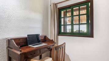Ein Holztisch mit einem Laptop, einem Stuhl und einem Fenster mit grünem Rahmen.