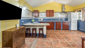Una cocina con salpicadero de azulejos, armarios de madera, una isla central con taburetes y un microondas empotrado.