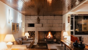 Una sala de estar acogedora con chimenea de piedra, techo de madera y asientos cómodos.