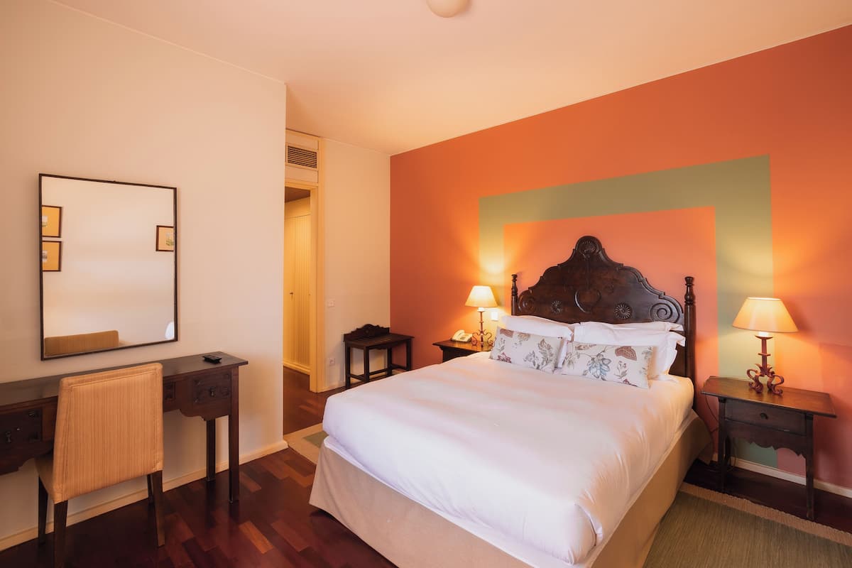 A hotel room with a bed, a desk, and a chair.
