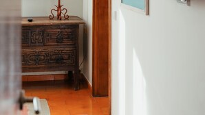Una habitación con un aparador de madera, una lámpara, un cuadro enmarcado y un televisor montado.