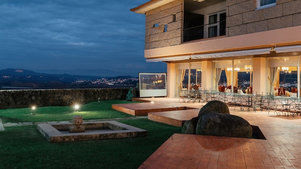 Un patio moderno al aire libre con pared de piedra, zona de estar y una pantalla grande.