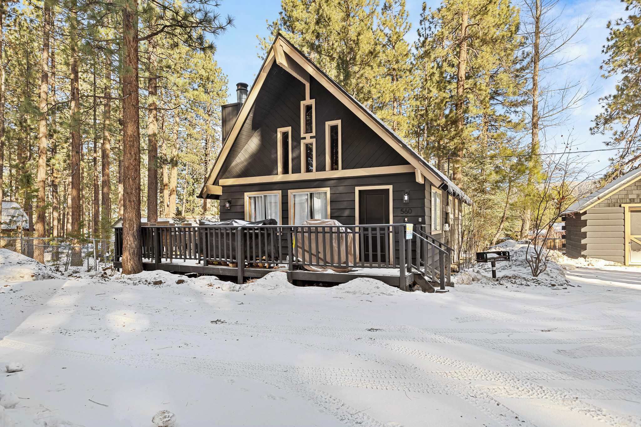 Una baita con esterno scuro, un molo di legno e terreno innevato.