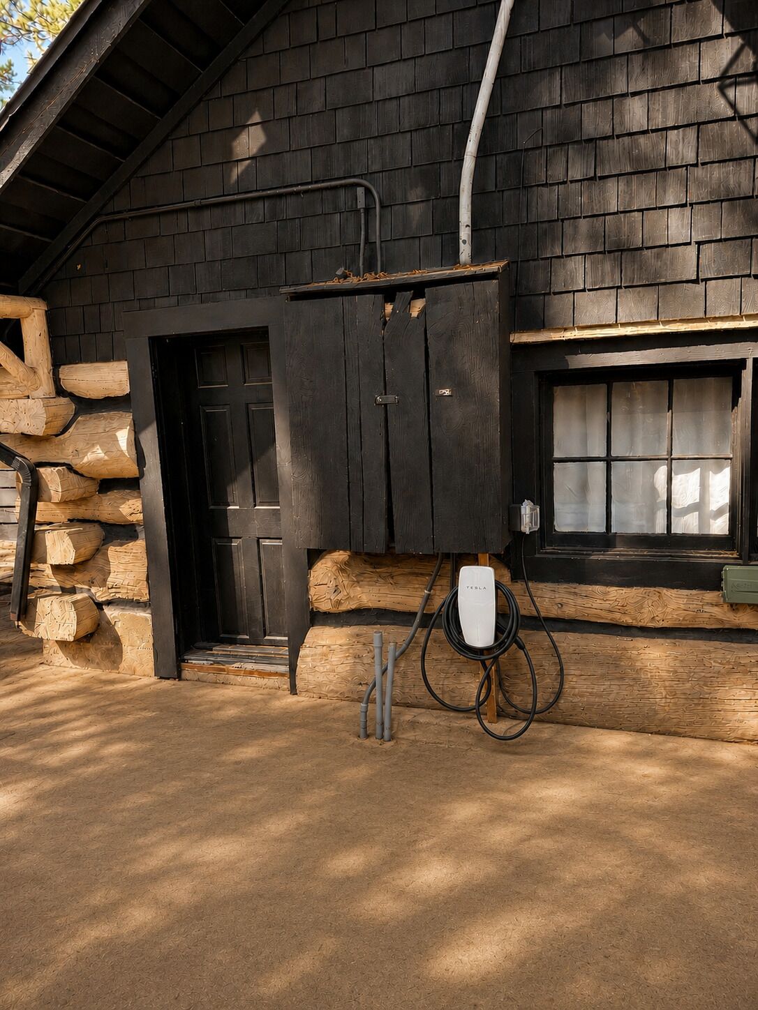 Un bâtiment rustique avec une façade en bois, une porte noire et une fenêtre ornée de rideaux.