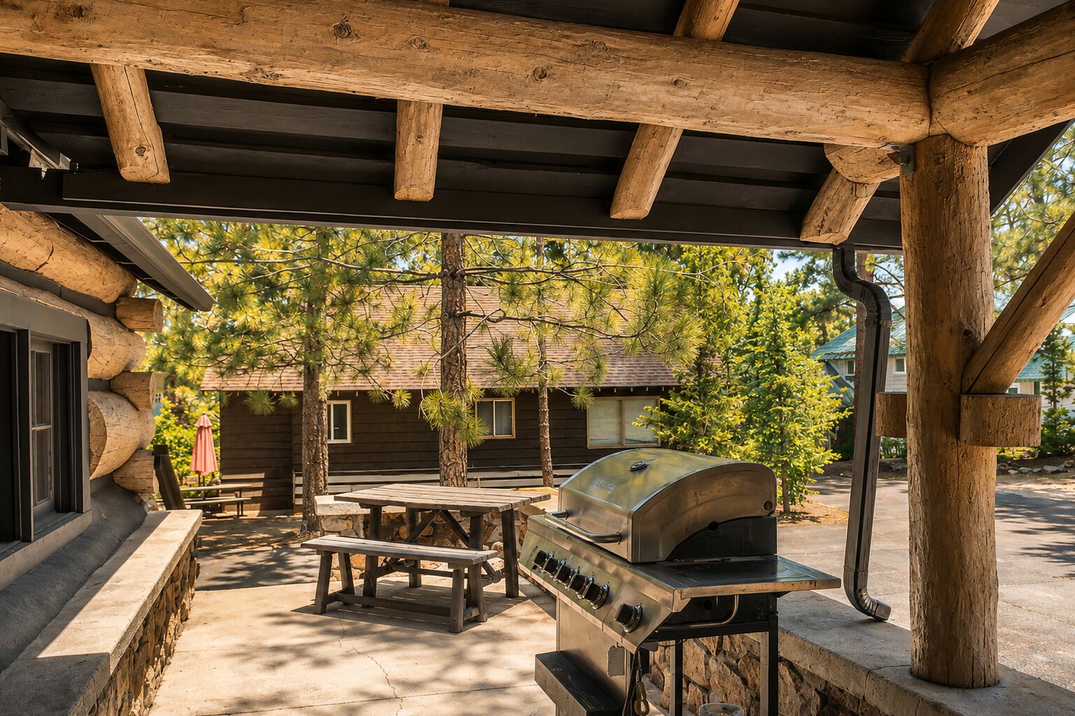 Un espace extérieur abrité comprenant un barbecue, une table de pique-nique et, au fond, une cabane en bois.