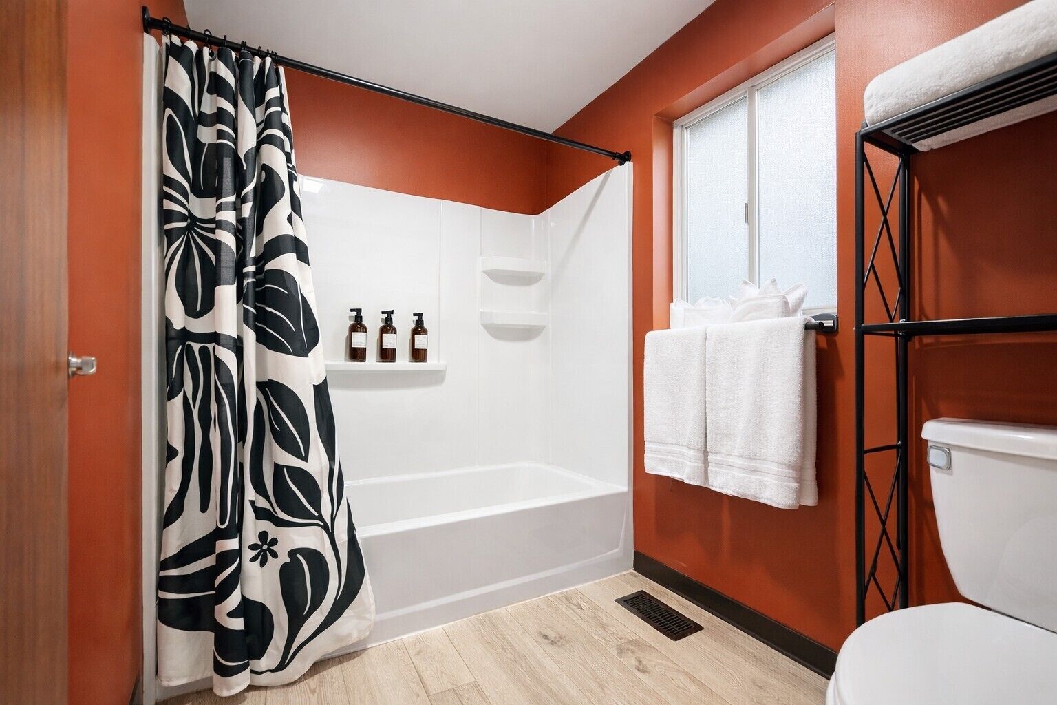 Une salle de bain avec un rideau de douche, une baignoire, des toilettes et une fenêtre.