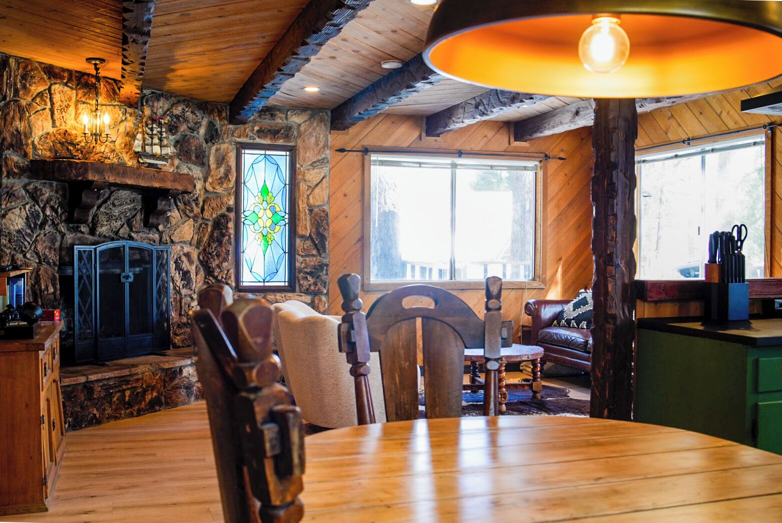 Un ambiente rustico con camino in pietra, tavolo da pranzo in legno e un'ampia finestra.