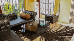 A living room with a black leather sofa, a glass coffee table, and a striped rug. - Zuri Resort Bungoma (Bungoma)