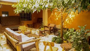 A cozy indoor seating area with a sofa, chairs, and a small table, surrounded by potted plants and a tiled floor. - Zuri Resort Bungoma (Bungoma)
