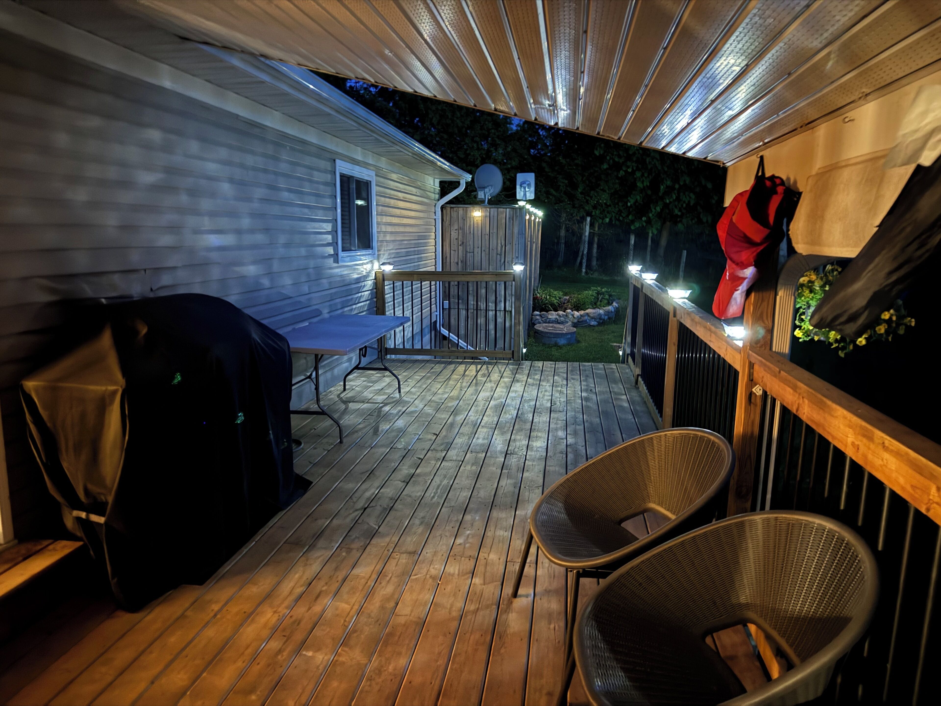 A wooden deck with a grill, chairs, and a small table.
