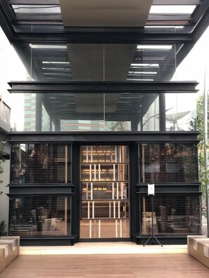 Een modern gebouw met een glazen gevel en een houten terras ervoor.