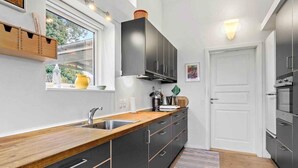 Een moderne keuken met zwarte kastjes, een houten aanrechtblad en een raam met uitzicht op groen.