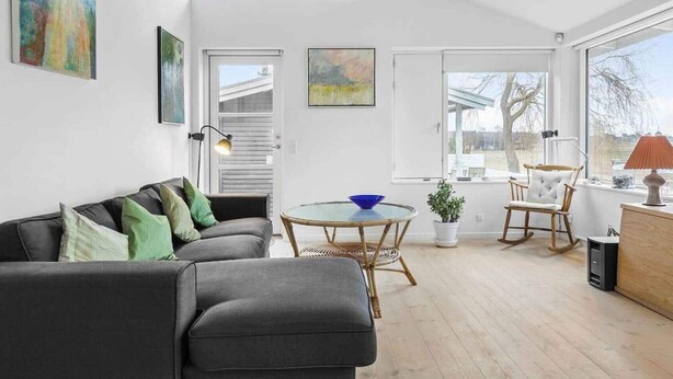 Een moderne woonkamer met een grijze bank, een glazen tafel en uitzicht op de omgeving.