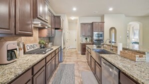 A modern kitchen with granite countertops, stainless steel appliances, and wooden cabinets. - Spacious Retreat Near Kalahari on an Acre, Updated Kitchen, Foosball, Screened Porch, Huge Backyard (Round Rock)