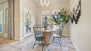 A dining area with a round table, four chairs, a chandelier, and a potted plant. - Spacious Retreat Near Kalahari on an Acre, Updated Kitchen, Foosball, Screened Porch, Huge Backyard (Round Rock)