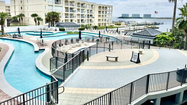 Un resort con una piscina grande, una palmera y vistas al puerto deportivo.