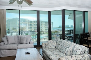 A living room with a sofa, a coffee table, and a view of a pool and buildings.