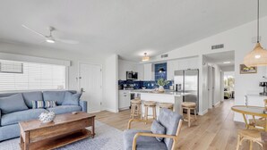 A spacious living area with a sofa, coffee table, and a kitchen in the background. - 2/2 Oceanview Retreat with Full Kitchen & Balcony-unit 8 (New Smyrna Beach)