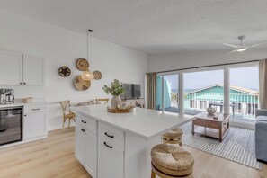 Eine moderne Küche mit weißen Schränken, einer zentralen Kochinsel und einem Essbereich mit Meerblick.