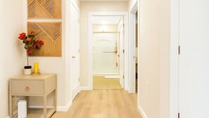 A hallway with wooden flooring, a white door on the right, and a white railing above. - Modern Loft near Yale and Wooster Square + Parking (New Haven)
