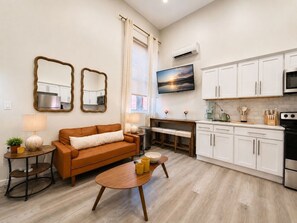 A modern kitchen with white cabinets, a black oven, and a dining area with a table and chairs.
