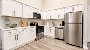 A modern kitchen with white cabinets, stainless steel appliances, and a wooden floor. - Modern Loft near Yale and Wooster Square + Parking (New Haven)