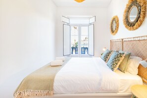 Un dormitorio con cama, mesita de noche y vistas a través de una puerta abierta.
