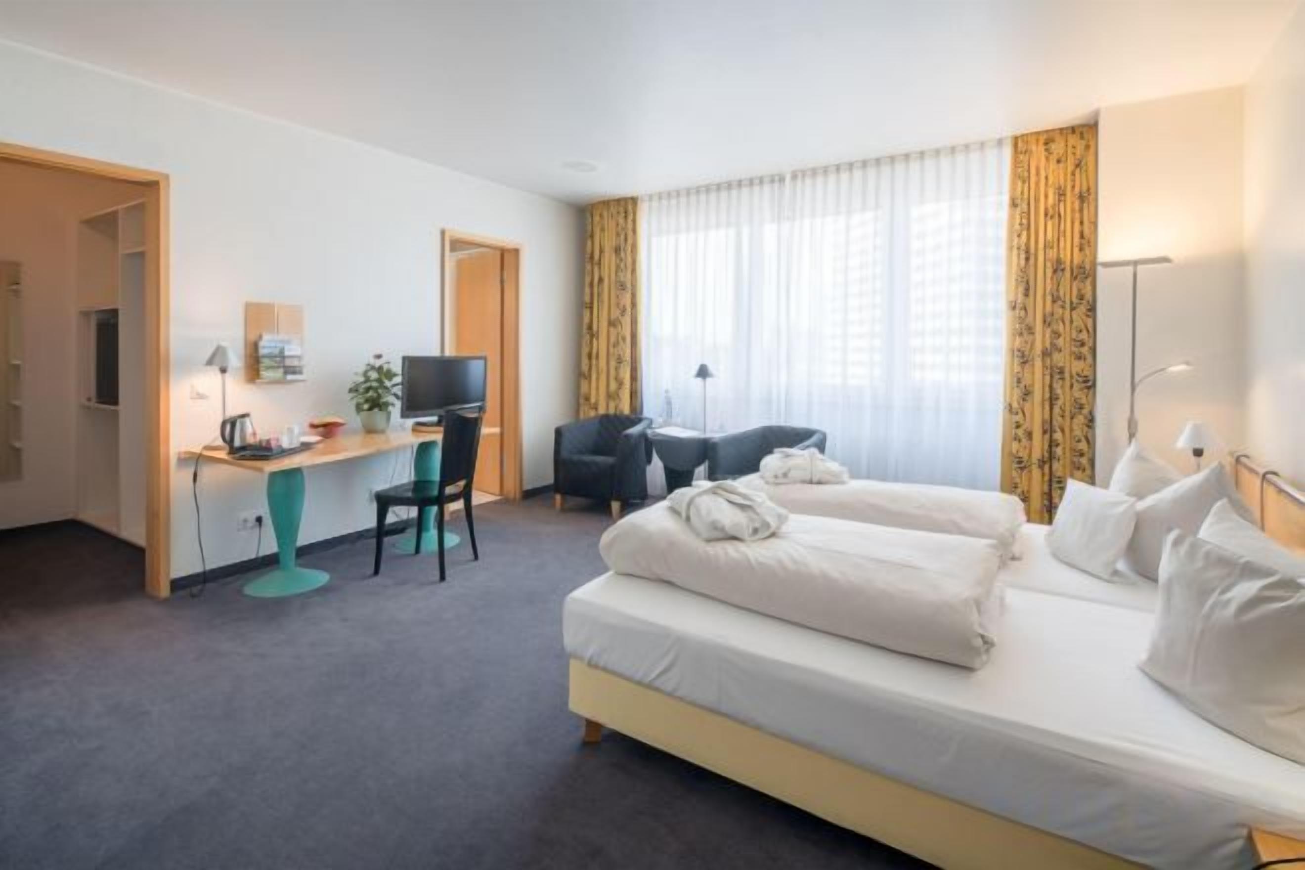 Une chambre d’hôtel équipée d’un lit, d’un bureau, d’une chaise, d’une télévision et de rideaux.