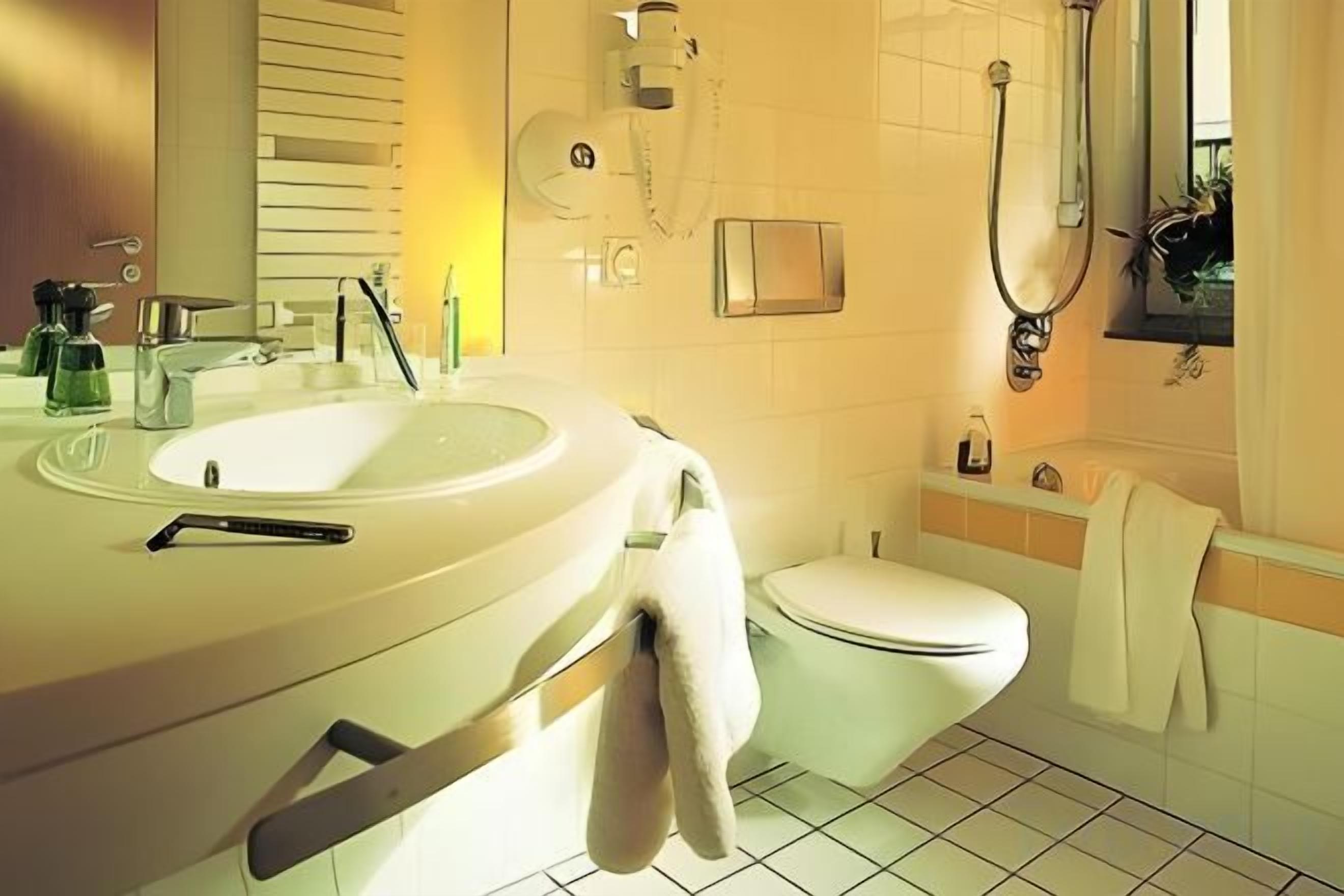Ein Badezimmer mit weißem Waschbecken, WC und Duschbereich.