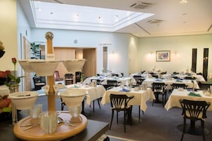 A dining area with tables set for service, a central decorative lamp, and a view of the dining hall.