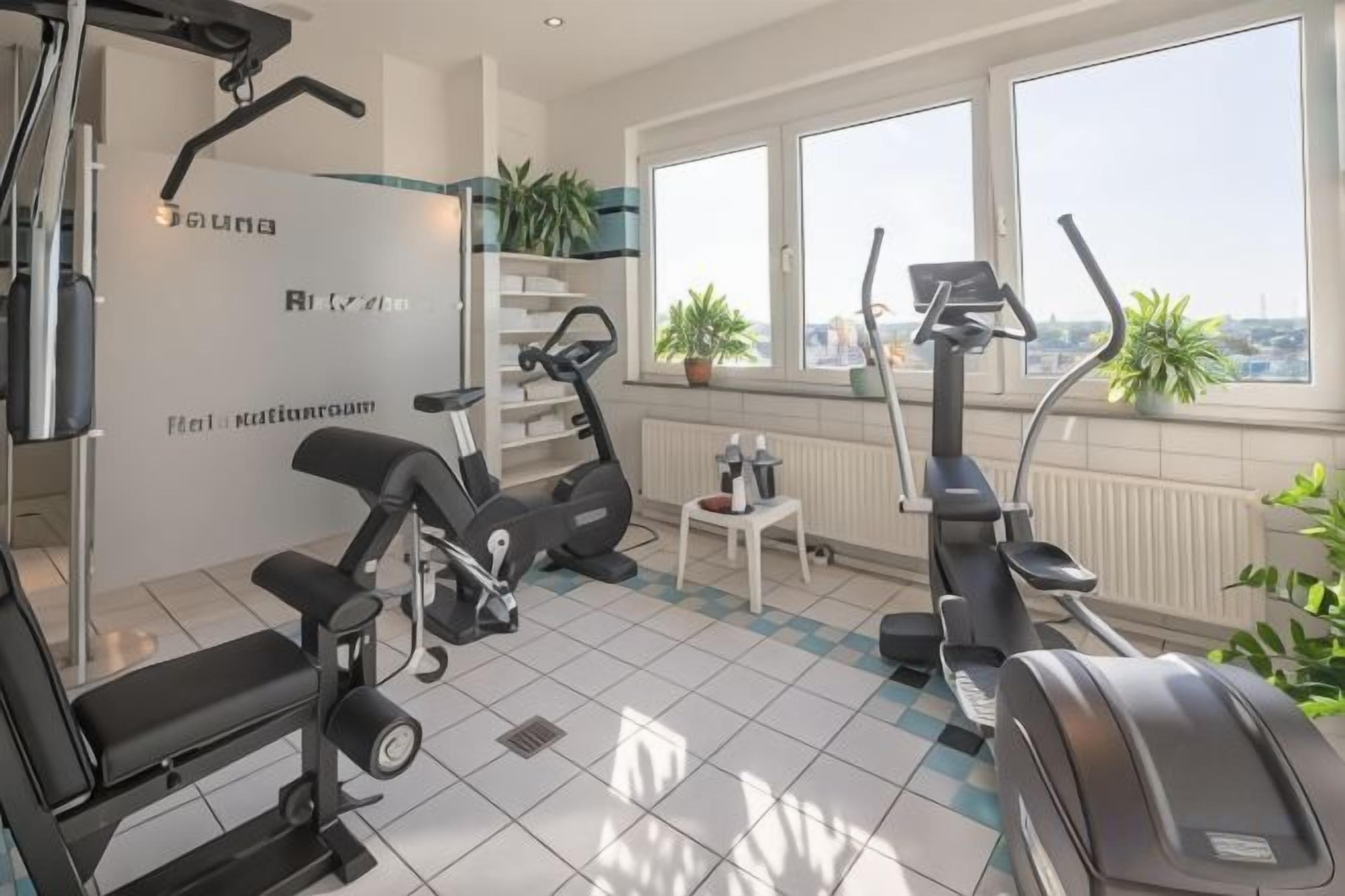 A gym with exercise equipment, a window with a view, and a radiator.