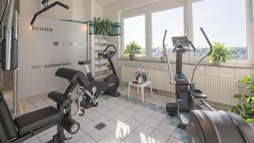 A gym with exercise equipment, a window with a view, and a radiator.