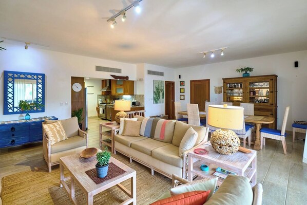 A spacious living area with a sofa, chairs, a coffee table, and a dining table with chairs.