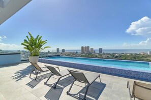 A rooftop pool with a city view, lounge chairs, and a potted plant. - ® La~Diana s~View @FarallonSD +Pool+Gym+Downtown (Santo Domingo)