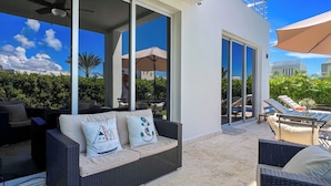 Ein moderner Außenbereich mit einer Couch, Lounge-Sesseln und Blick auf einen Pool.