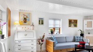 Una sala de estar acogedora con un aparador blanco, un sofá, una silla de madera y una mesita.