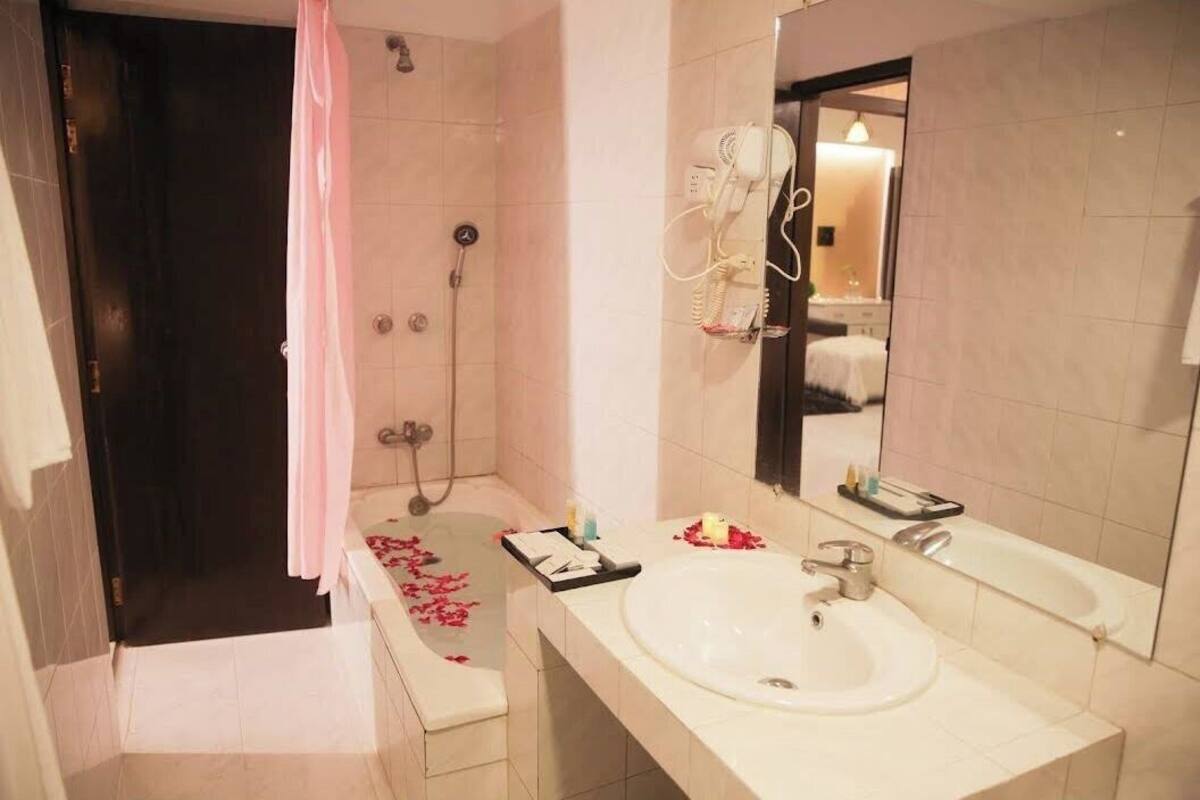 A bathroom with a bathtub, a shower, a sink, and a mirror.