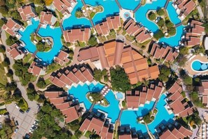 A resort with multiple swimming pools, arranged in a circular pattern, surrounded by uniformly designed buildings.