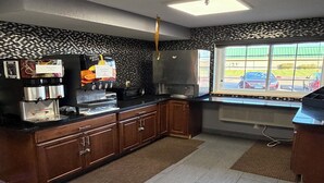 A kitchen with a coffee station, a refrigerator, and a window with a view of parked cars. - Coratel Inn and Suites by Jasper Stillwater Standard 1 King Bed Non Smoking (Stillwater)