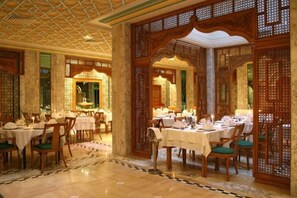 A dining area with tables set for service, wooden partitions, and a patterned floor. - El Mouradi Mahdia (Mahdia)