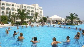 A swimming pool surrounded by palm trees and a hotel building. - El Mouradi Mahdia (Mahdia)
