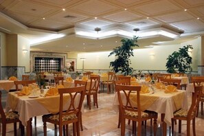 A dining area with tables set for service, a large plant, and a patterned wall in the background. - El Mouradi Mahdia (Mahdia)