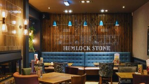 A restaurant interior with a blue upholstered booth, wooden panel wall, and blue pendant lighting.