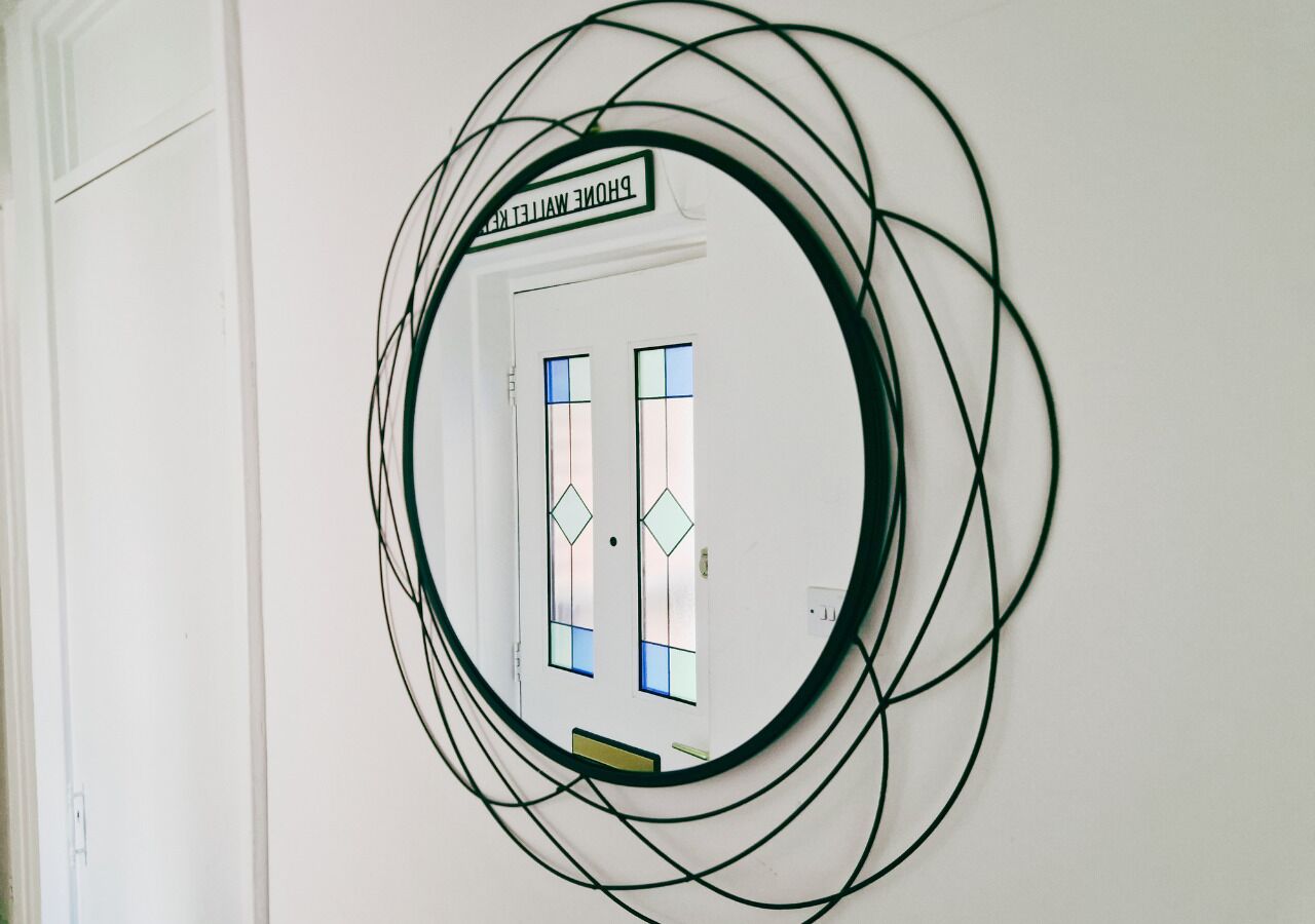 A circular mirror with a black frame on a white wall.