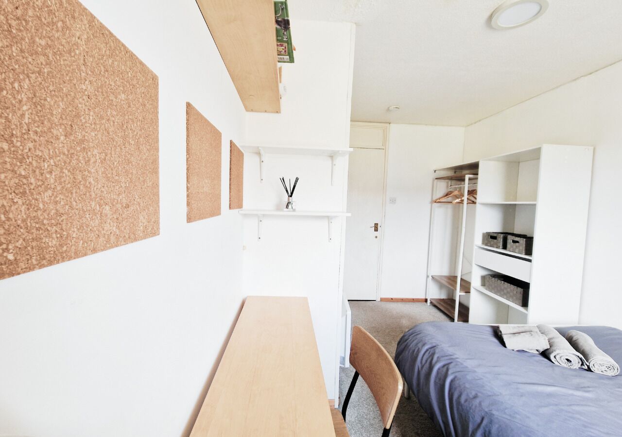 A modern bedroom with a bed, a desk, and a wardrobe.