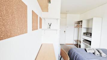 A modern bedroom with a bed, a desk, and a wardrobe.