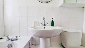 Une salle de bain avec un lavabo blanc, une baignoire et des toilettes.